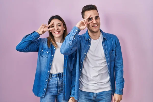 Unga Latinamerikanska Par Står Över Rosa Bakgrund Gör Fred Symbol — Stockfoto