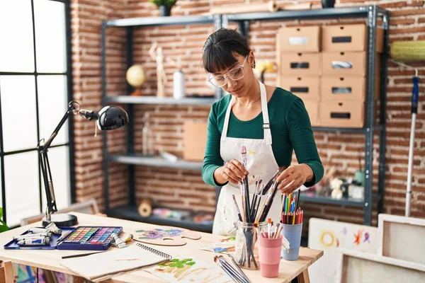 Young Beautiful Hispanic Woman Artist Holding Paintbrushes Art Studio — Stockfoto