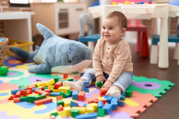 幼稚園で床に座っている木製の建設ブロックで遊んで愛らしい幼児 — ストック写真