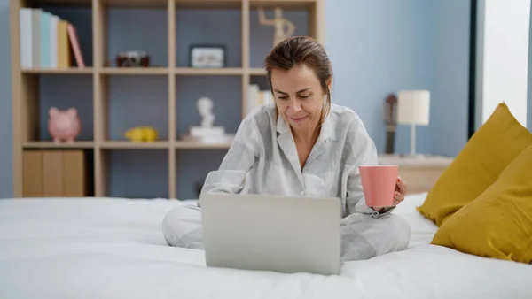 Mulher Hispânica Meia Idade Usando Laptop Beber Café Sentado Cama — Fotografia de Stock