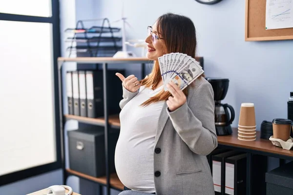 Těhotná Žena Drží Dolary Kanceláři Ukazuje Palcem Nahoru Stranu Usmívá — Stock fotografie