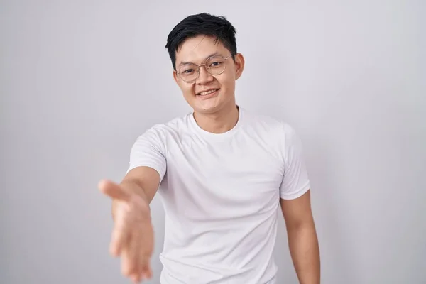 Young Asian Man Standing White Background Smiling Friendly Offering Handshake — Stockfoto