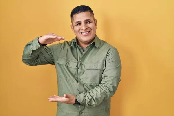 Латиноамериканец Стоит Жёлтом Фоне Жестикулирует Руками Показывая Большой Большой Знак — стоковое фото