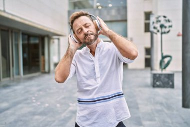 Şehirde müzik dinleyen orta yaşlı bir adam.