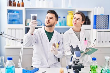 Man and woman wearing scientist uniform working at laboratory