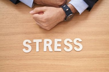Young hispanic man business worker sitting on table with stress word at office