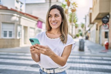 Sokakta akıllı telefon kullanan, kendine güvenen genç İspanyol kadın.