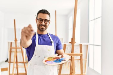 Genç İspanyol adam resim stüdyosunda kendine güvenen gülümsüyor.