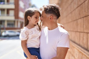 Father and daughter smiling confident hugging each other at street