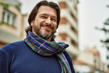 Kasabada gülümseyen orta yaşlı yakışıklı bir adam.