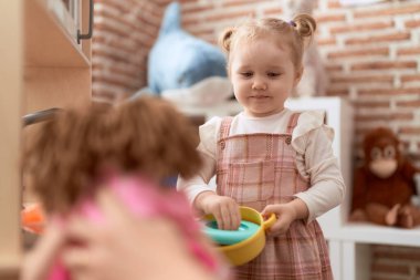 Sevimli beyaz kız kreşte oyun mutfağıyla oynuyor.