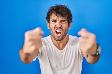 Latin kökenli genç adam öfkeyle bağırırken kızgın ve kızgın yumruklarını kaldırıyor. öfke ve agresif konsept. 