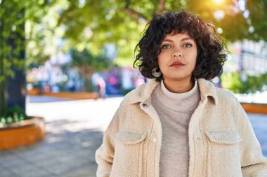 Parkta ciddi bir ifadeyle duran genç, güzel İspanyol kadın.