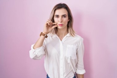 Pembe arka planda duran genç ve güzel bir kadın ağzı ve parmakları fermuar gibi kapalı dudakları var. gizli ve sessiz, tabu konuşması 