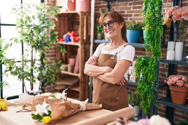 Middle age woman florist smiling confident standing with arms crossed gesture at flower shop