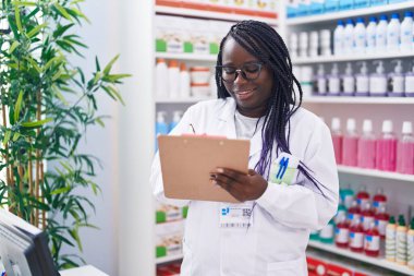 Afrika kökenli Amerikalı kadın eczacı eczanedeki belgeye yazı yazıyor.