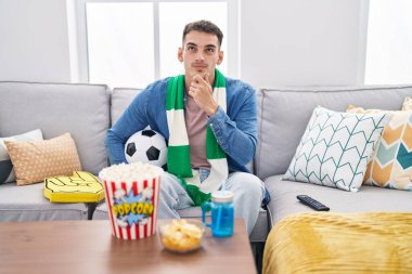 Yakışıklı İspanyol adam top destekleyici takımı tutuyor ciddi yüz soru soruyor çene ve çene üzerine kafa karıştırıcı bir fikir. 