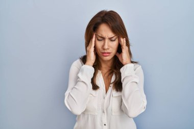 Hispanic woman standing over isolated background with hand on head, headache because stress. suffering migraine. 