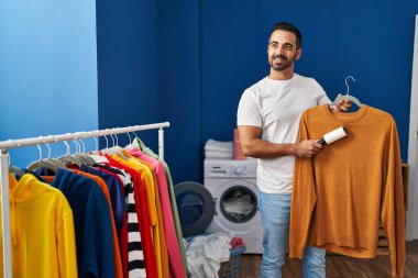 Çamaşır odasında kuaförle süveter temizleyen İspanyol genç adam.