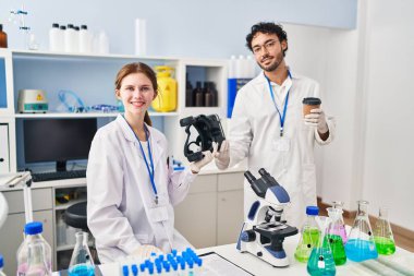 Erkek ve kadın bilim adamı partnerler VR gözlükleri tutuyor ve laboratuvarda kahve içiyorlar.