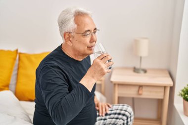 Usta yatak odasında bir bardak su içiyor.