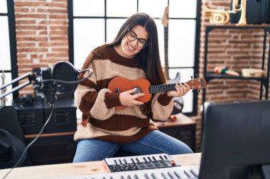 Genç İspanyol kadın müzisyen müzik stüdyosunda ukulele çalıyor.