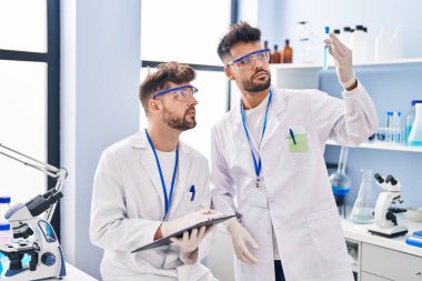 Young couple wearing scientist uniform working at laboratory