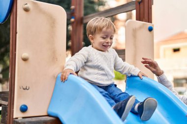 Mother and son playing on slide at park