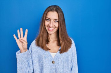 Mavi arka planda duran genç bir kadın dört numarayı gösterip işaret ederken kendinden emin ve mutlu bir şekilde gülümsüyor.. 