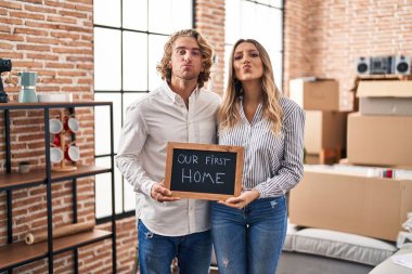 Genç çift yeni bir eve taşınıyor. Kameraya bakıp öpüşüyorlar. Sevimli ve seksi oluyorlar. aşk ifadesi. 