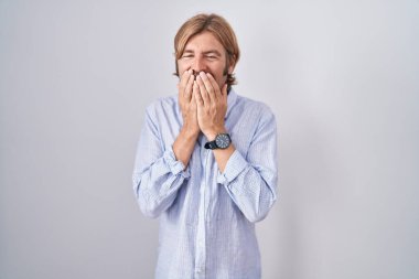 Caucasian man with mustache standing over white background laughing and embarrassed giggle covering mouth with hands, gossip and scandal concept 