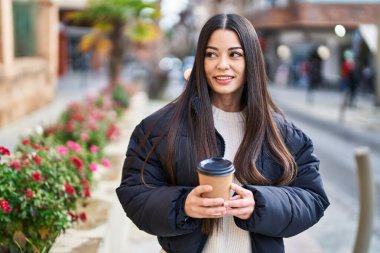 Young beautiful hispanic woman smiling confident drinking coffee at street