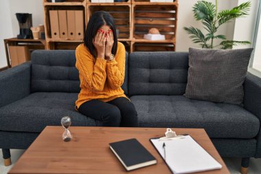 Psikoloji seansı geçiren genç Latin kadın klinikte ağlıyor.