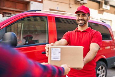 Genç İspanyol kurye sokakta paket veriyor.