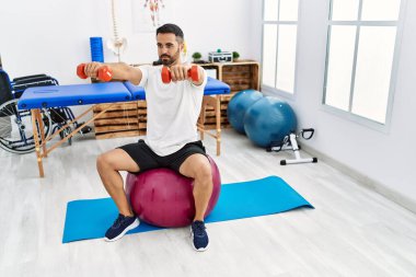 Genç İspanyol hasta rehabilitasyon seansı için klinikteki halterleri ve topları kullanıyor.