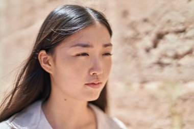 Çinli kadın sokakta rahat bir ifadeyle yan tarafa bakıyor.