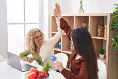 Evde dizüstü bilgisayar ve kredi kartı kullanan iki kadın anne ve kız