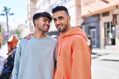 İki erkek caddede birbirlerine sarılıyorlar.