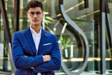 Genç adam sokakta takım elbise ve gözlük takarak rahatladı.