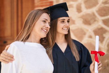 Two women mother and graduated daughter standing together at campus university