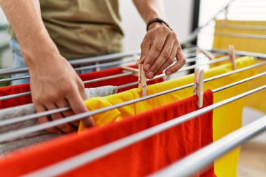 Young caucasian man hanging clothes at laundry room