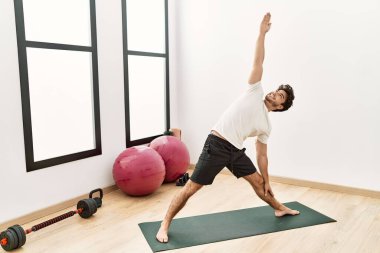 Genç İspanyol adam gülümsüyor spor merkezinde yoga antrenmanı yapıyor.