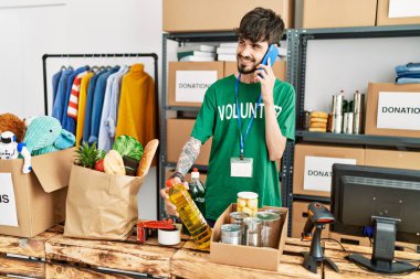 Gönüllü üniformalı genç İspanyol bir adam yardım merkezindeki akıllı telefondan konuşuyor..