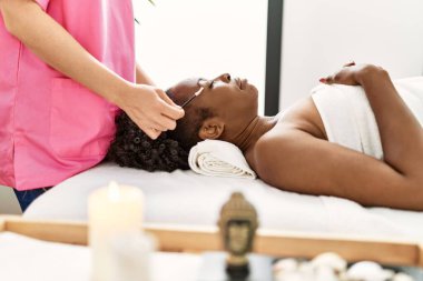 African american woman lying on massage table having eyebrows treatment at beauty salon