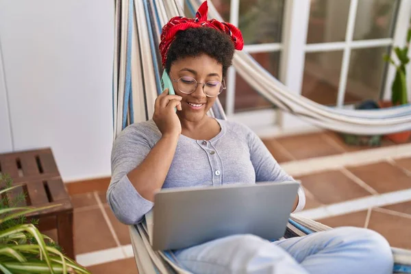 Mujer Afroamericana Usando Laptop Hablando Smartphone Tumbado Hamaca Casa Terraza — Foto de Stock