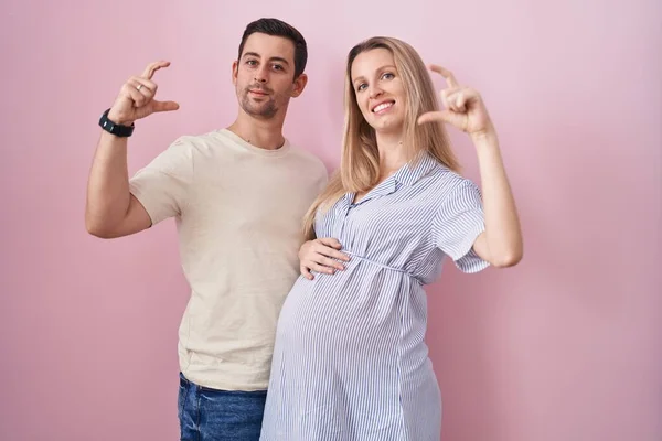 Junges Paar Erwartet Ein Baby Vor Rosa Hintergrund Lächelnd Und — Stockfoto