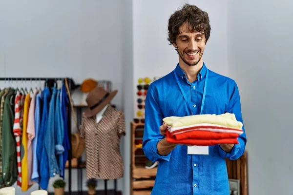 Mladý Hispánec Usmívá Sebevědomě Drží Složené Oblečení Obchodě Oblečením — Stock fotografie