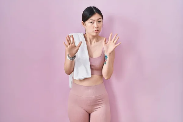 スポーツウェアとタオルを身に着けている中国の若い女性は 恐怖と嫌な表情で拒否と否定を示す手のひらを離れて移動します 止めて禁止する — ストック写真