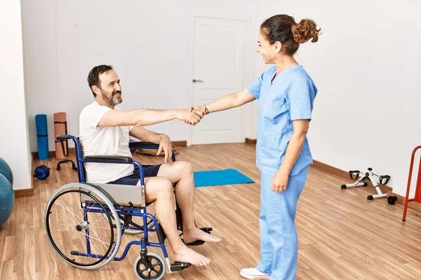 Middle age man and woman smiling confident having physiotherapy session shake hands at physiotherapy clinic