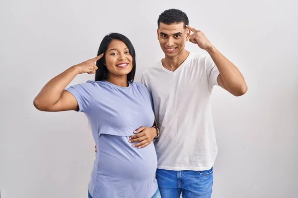 Young Hispanic Couple Expecting Baby Standing Background Smiling Pointing Head —  Fotos de Stock
